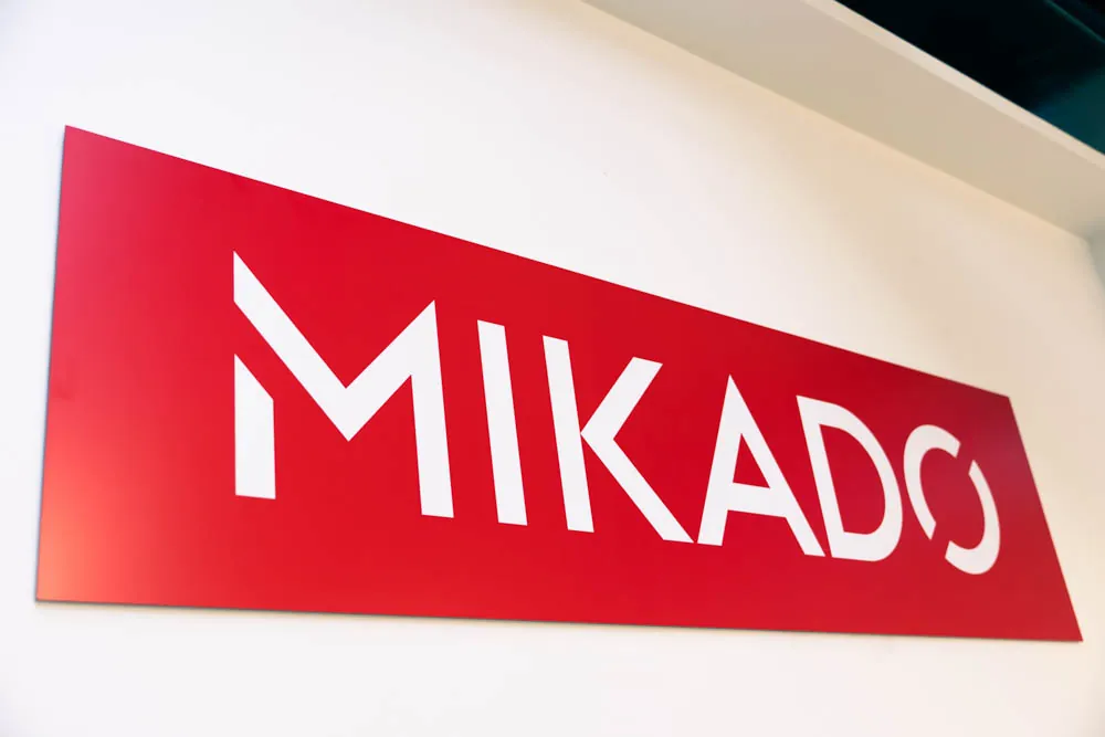 Le logo Mikado, plaque rouge sur un mur blanc de l'agence