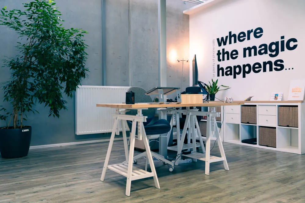 Un poste de travail devant le lettrage mural « where the magic happens »