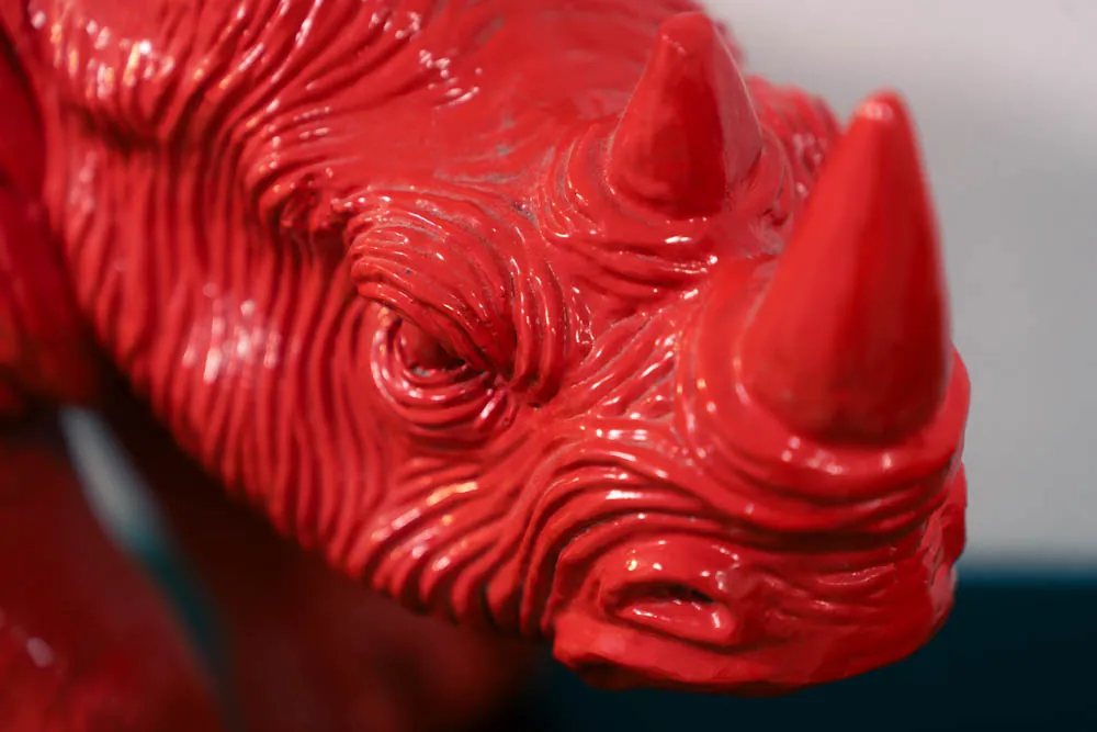 Gros plan sur un rhinocéros rouge en résine, posé dans les bureaux