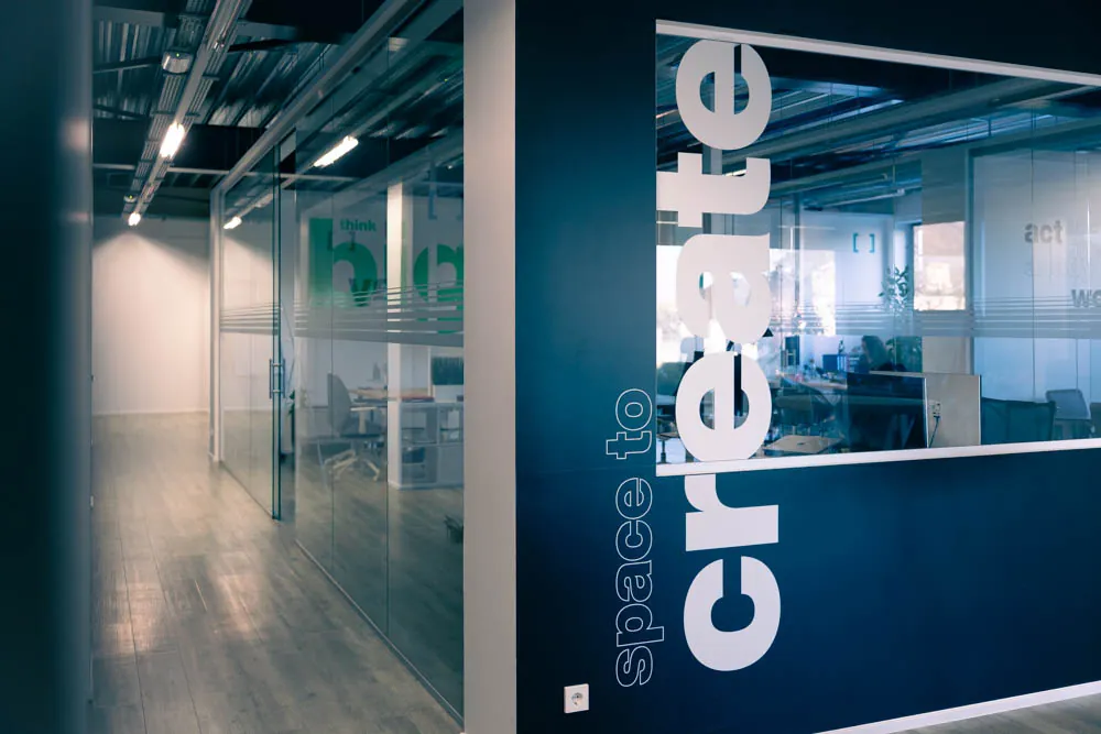 Couloir vitré de l'agence, portant le lettrage « space to create »