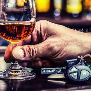 un verre de cognac rempli qui vient d'être soulevé avec les clés de la voiture qui se trouvent à côté
